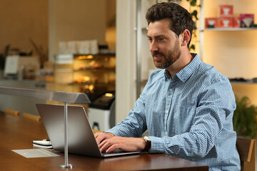 Fototapeta na wymiar Man working on laptop at table in cafe