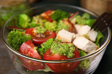Delicious salad with pesto sauce in bowl on table, closeup
