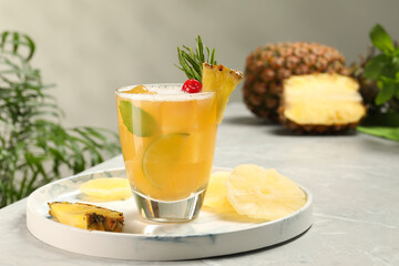 Glass of tasty pineapple cocktail and fresh fruit on light gray table