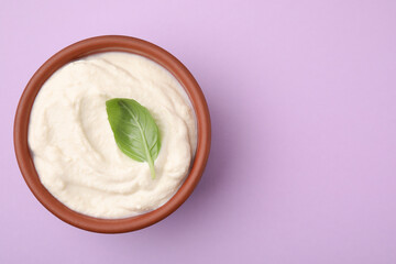 Delicious tofu sauce and basil leaf in bowl on violet background, top view. Space for text