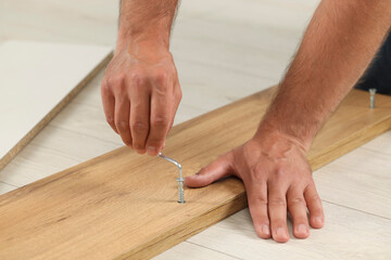 Man with hex key assembling furniture on floor, closeup