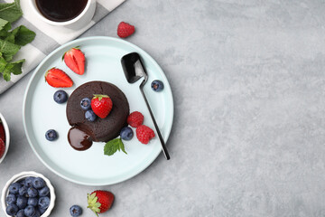 Plate with delicious chocolate fondant, berries and mint on grey table, flat lay. Space for text
