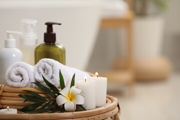 Fototapeta na wymiar Spa products, burning candles, plumeria flower and tropical leaf on table in bathroom. Space for text