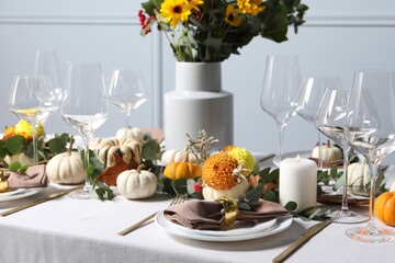 Beautiful autumn table setting with bouquet indoors. Plates, cutlery, glasses and floral decor