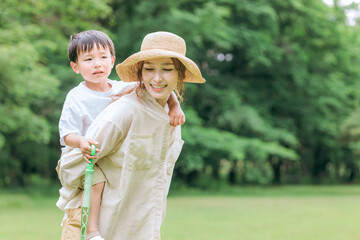 公園で泣く子供をおんぶしてあやすママ・母親
