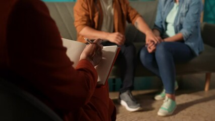 A marriage therapist notes in a notebook the goals the couple has achieved through their sessions together. Notebook with notes in the hands of a female psychologist against a close up.
