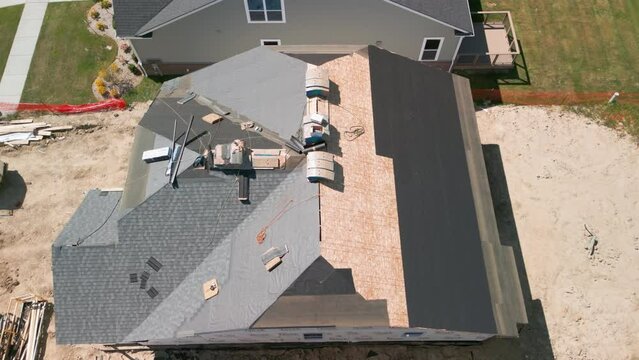 Roofer repair or replace shingle that has been damaged and needing replacement at sunny day. Wide shot aerial view