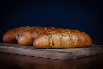 Garlic bread stuffed with cheese on a cutting board on a wooden table. Rustic bread, hand made.