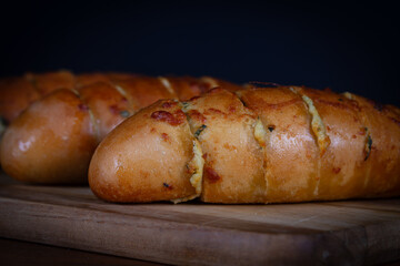 Garlic bread stuffed with cheese on a cutting board on a wooden table. Rustic bread, hand made.