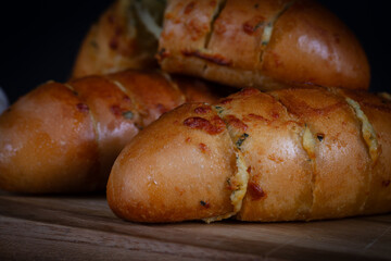 Garlic bread stuffed with cheese on a cutting board on a wooden table. Rustic bread, hand made.