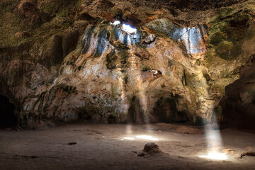 Quadiriki cave in Arikok National Park, Aruba. Sunbeams extend from openings in the cavern roof to...