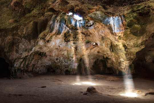 Quadiriki cave in Arikok National Park, Aruba. Sunbeams extend from openings in the cavern roof to the floor. 
