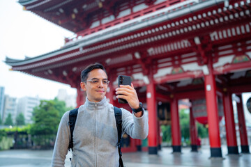Soft focus of happy Hispanic happy tourist with backpack standing near Japanese Sensoji temple in...