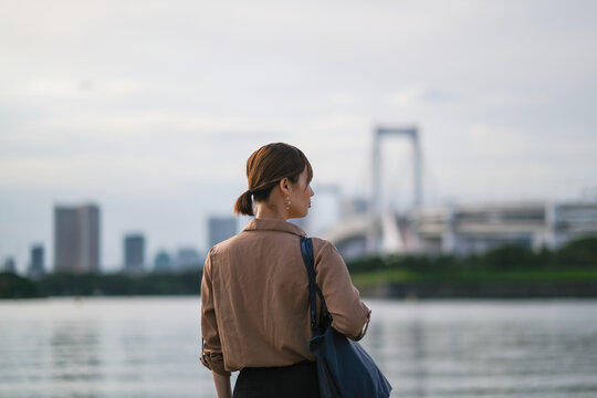 ベイエリアの景色を眺めるビジネスウーマンの後ろ姿