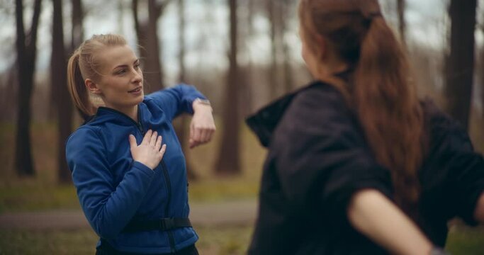 Woman practicing shoulder exercise with female friend