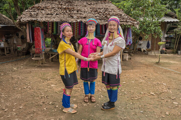 three long-necked Karen women with brass neck rings and traditional Karen dress showing Karen dance...