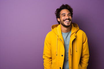 Colourful portrait of a handsome happy man laughing and smiling wearing yellow jacket on bright purple background - obrazy, fototapety, plakaty
