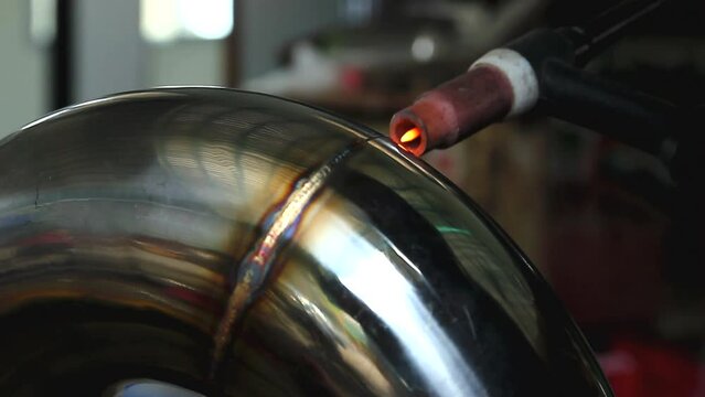 Welder is welding the stainless steel pipes in the factory