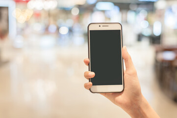 Woman hand holding using smartphone at shopping center