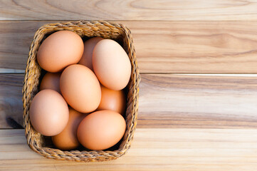 Chicken eggs in basket on wooden background
