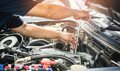 Auto mechanic working on car engine repair and maintenance in a garage