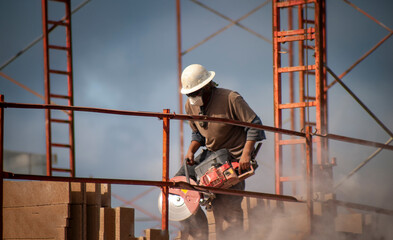 Construction worker wearing a hard hat operating a circular saw ar a job site with metal framing
