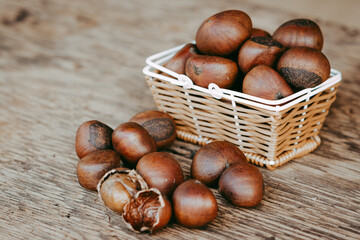 Chestnuts in mini basket on wooden background