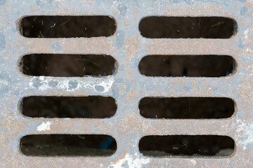 Manhole cover drainage grille on the road floor.