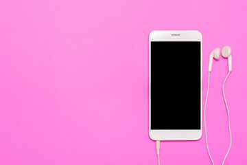 White smartphone with earphone on pink background