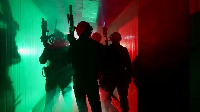 A group of special forces soldiers in combat gear in a building with neon lighting and smoke. A soldier with a machine gun in a helmet and army equipment.