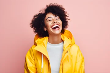 Zelfklevend Fotobehang Colourful portrait of a young black happy beauty woman laughing and smiling wearing yellow hoody on bright pink background © sam