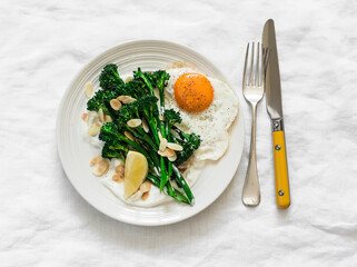 Grilled broccolini with greek yogurt and toasted almonds and fried egg on a light background. Delicious breakfast, brunch