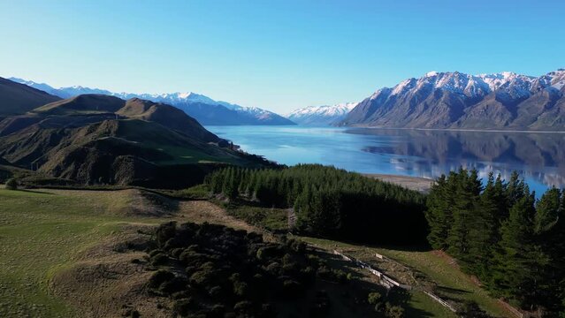Hawea, New Zealand: Dramatic aerial drone footage of the coastal raod along lake Hawea in Wanaka on a sunny winter in New Zealand south island.