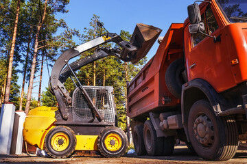Excavator with wheel loader with backhoe loads unloading clay or gravel into truck. skid loader © Sergey