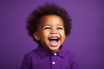 Portrait of a cute African American baby boy wearing purple shirt laughing on bright purple...