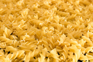Uncooed Fusilli Pasta - Background. Texture of Bright Golden Dry Macaroni