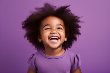 Portrait of a cute African American baby girl wearing purple tee shirt laughing on bright purple background