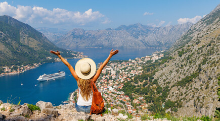Rear view of woman with open arms enjoying panoramic view of Kotor Bay- travel, tour tourism, vacation in Montenegro, Europe