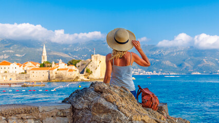 tour tourism,  vacation, travel destination in Montenegro- Woman tourist sitting on rock looking at...