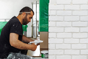 Man decorates the wall with decorative white torn bricks, close up view, DIY