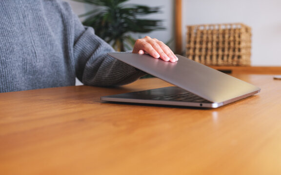 Closeup image of a woman close and open a laptop computer on table after finished using it