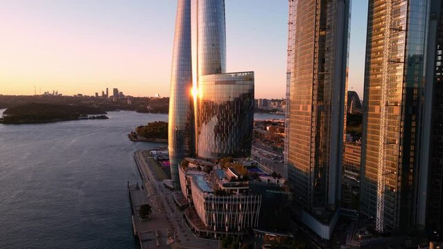 Sydney, Australia: Aerial drone footage of the stunning Sydney harbor with the iconic bridge with a revealing motion behind the new skyscrapers in Darling Harbor in Sydney at sunset. 