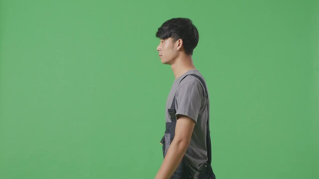 Side View Of Asian Man Worker Walking In The Green Screen Background Studio
