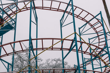 Ferris wheel in the winter park in winter during the appearance of fog. Fog in winter at the amusement park. Rides in the park in winter. Fog in the city park. Entertainment for vacationers.