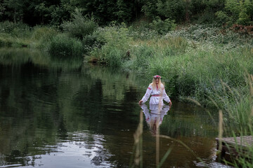 Portrait of a young beautiful blonde girl near a pond.