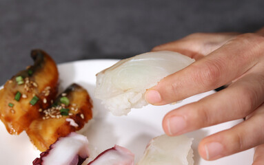Close-up images of healthy and fresh sushi. Close-up image of holding flatfish sushi with hands.
