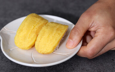 Close-up images of healthy and fresh sushi. Close-up image of picking up egg sushi with fingers.
