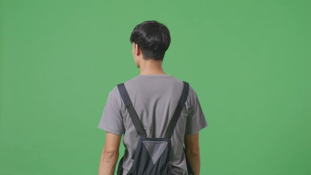 Back View Of Asian Man Worker Walking And Looking Around In The Green Screen Background Studio
