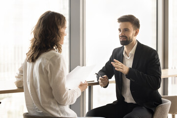 Positive young professional coworkers discussing project reports, legal documents cooperation,...