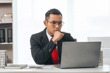 Fototapeta premium Agent presents contracts for property purchase or lease. Businessman asian indian people showcases miniature model home, signifying secure property insurance. Desk scene in a home sales office.